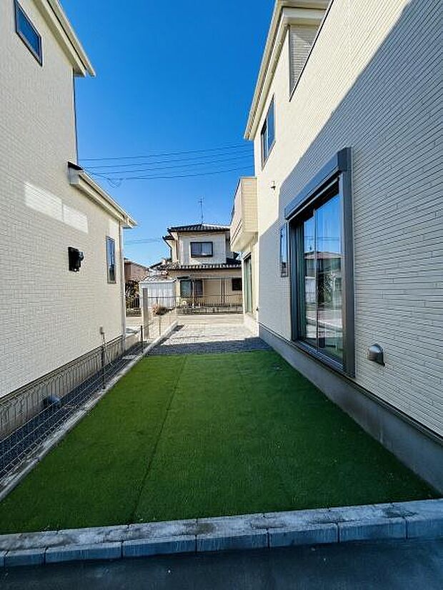 手入れがしやすいシンプルな庭スペースとなっています。人工芝が敷かれており季節を問わず緑を感じられます。建物の間に位置しているためプライベートな空間として利用しやすい点も特徴です。