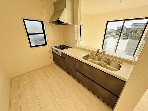 キッチンは窓があり明るい空間が広がります。広々とした作業スペースが確保されています。収納も豊富で整理しやすい仕様です。シンクやコンロの配置も使いやすさを感じられます。清潔感のある床材が印象的です。