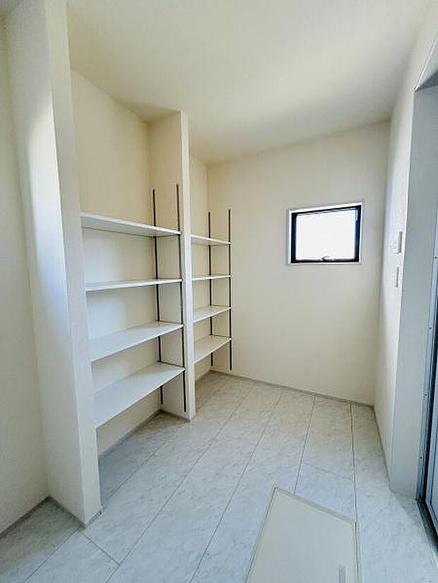 洗面所には壁一面のオープン棚が備え付けられており収納力があります。窓から採光があり明るさを感じる空間です。すっきりとした白を基調とした内装で印象的です。