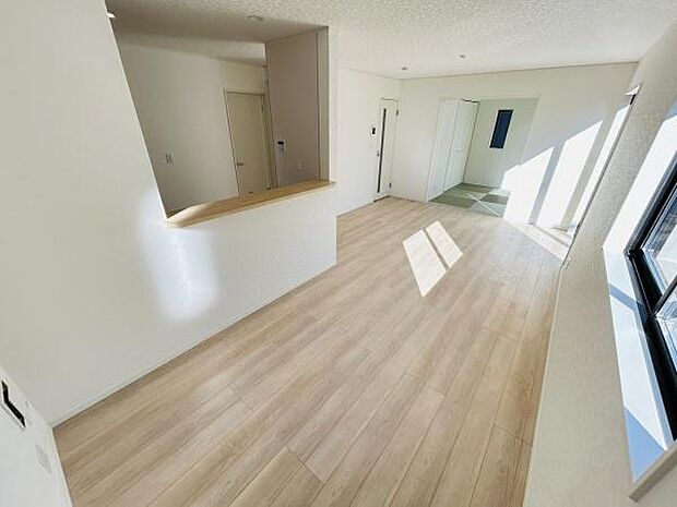 リビングは大きな窓から光が差し込み明るさが印象的です。開放感のある空間が広がっています。ナチュラルな色合いのフローリングが特徴です。隣接する和室スペースも魅力的です。