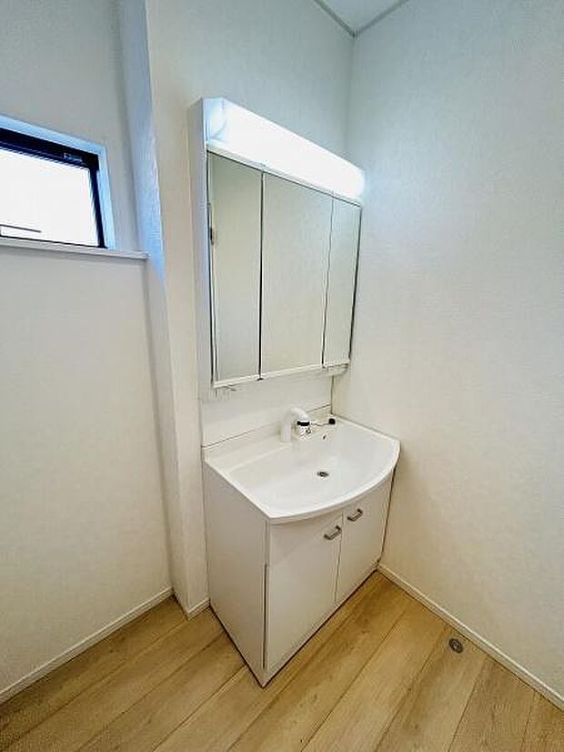 明るい照明付きの洗面台が設置されています。収納スペースがあり使いやすさも考慮されています。シンプルなデザインが空間に調和しています。窓があり換気もしやすいです。清潔感のある空間に仕上がっています。