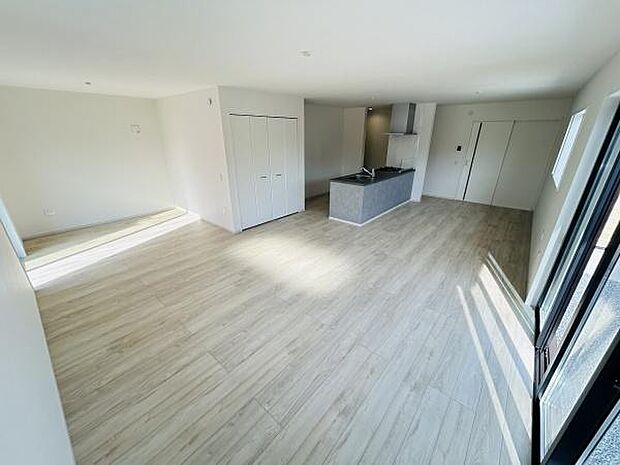 大きな窓からたっぷりと自然光が差し込みリビング空間が明るく広々としています。床材の色合いが全体をやわらかくまとめています。キッチンとリビングが一体となった設計ですので空間を有効に活かせます。