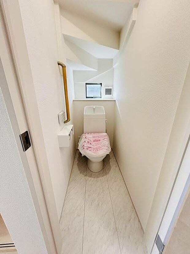 白を基調とした清潔感のあるトイレです。コンパクトな空間ながら窓から自然光が差し込みます。小物置きなどもあり使い勝手も良好です。換気や採光に配慮された設計です。