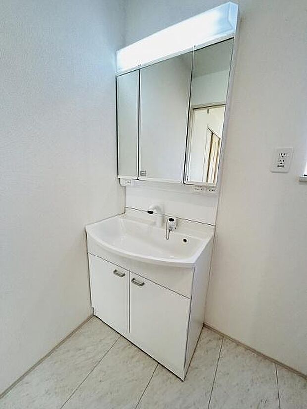 三面鏡つきの洗面台で毎日の身支度がしやすい仕様です。収納スペースも備わっており日用品の整理に便利です。シンプルなデザインが空間をすっきり見せます。清潔感のある内装が印象的です。