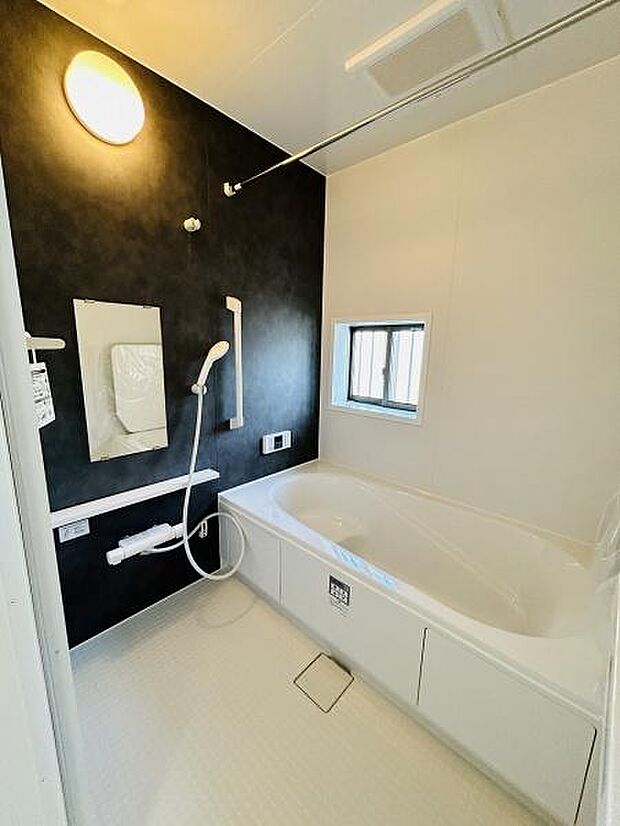 モノトーンの配色が印象的なバスルームです。浴室乾燥機や手すり付きで使いやすい仕様となっています。窓から外光が入り明るい雰囲気が広がります。洗い場もゆとりがあり快適に利用できます。