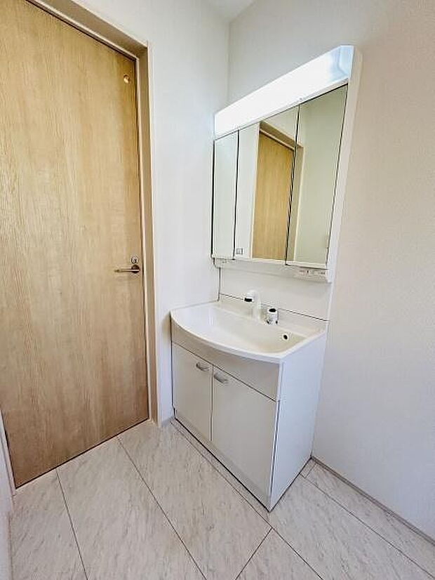 清潔感のある洗面台が設置されています。鏡が大きく使いやすいデザインです。収納スペースも充実しています。明るい空間で快適にご利用いただけます。