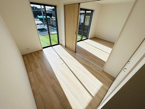 明るい日差しが差し込む洋室です。床は木目調で温かみがあります。スライドドアによる空間の有効活用が可能です。二面採光で開放感があります。室内はすっきりとした印象です。