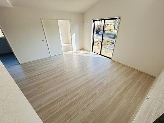 リビングは明るい日差しが差し込み開放感のある空間です。床材はナチュラルな色合いで落ち着いた印象を与えます。大きな窓から室外の景色も楽しめます。