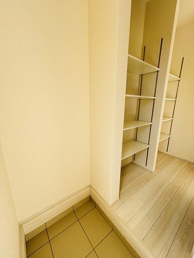 玄関には収納棚が設けられており使い勝手のよい空間です。明るい雰囲気が感じられる内装です。タイル部分が区切られており靴の収納に便利です。段差があるため室内への導線が分かりやすいです。