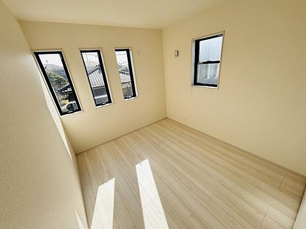 四つの小窓から光が差し込む明るい洋室です。壁や床がシンプルでお手入れしやすい仕様となっています。窓から心地よい風を取り入れられる工夫が感じられます。
