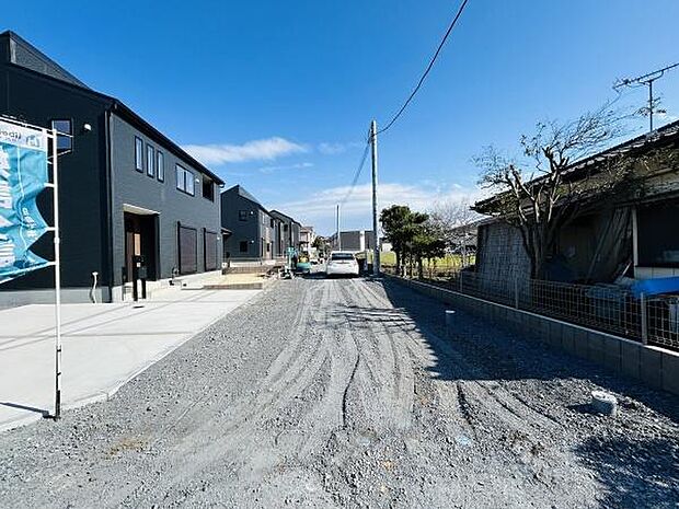 広々とした前面道路が印象的な現地写真です。周囲には新しい住宅が並び整然とした街並みが広がっています。日当たりの良い環境で通行や駐車にも便利な道幅です。整備されたエリアで生活の利便性も感じられます。