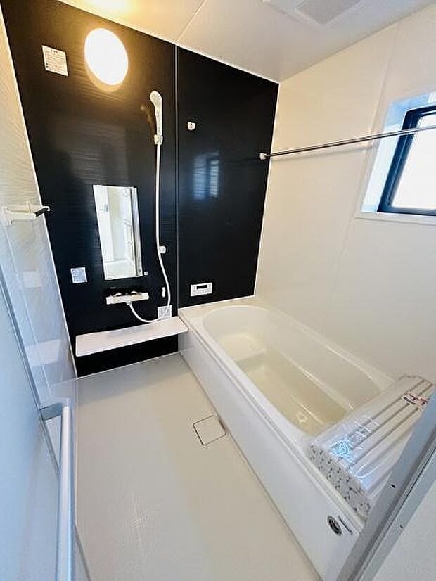 清潔感のあるバスルームです。黒と白のコントラストがアクセントになっています。大きな鏡と窓があり空間を広く感じられます。浴槽はゆったりとしたサイズです。シャワーや水栓も使いやすい配置となっています。