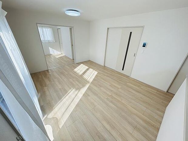 明るい陽射しが差し込むリビングです。ナチュラルな床材が空間をやわらかく演出しています。可動式の扉が空間を自在に仕切れる仕様です。室内の開放感が感じられる設計となっています。