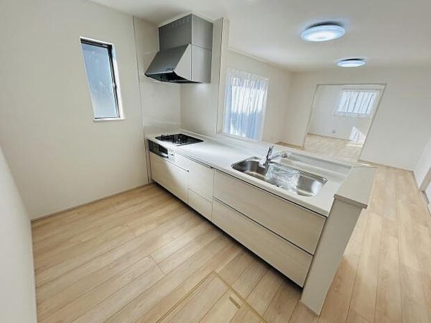 明るい室内に調和したキッチンです。広々とした作業スペースが魅力です。窓からの自然光がしっかり入ります。清潔感のあるホワイト基調でまとまっています。収納もしっかり確保されています。