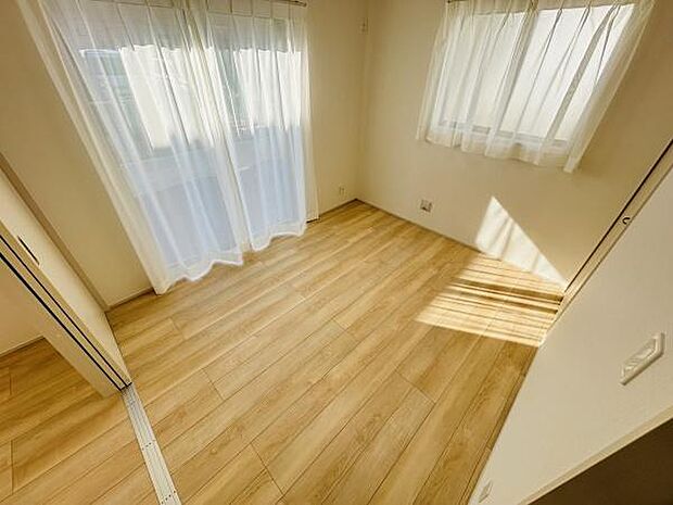 大きな窓から自然光がたっぷりと入る洋室です。明るいフローリングが室内全体を開放的に見せています。窓にはカーテンが設置されておりプライバシーにも配慮されています。