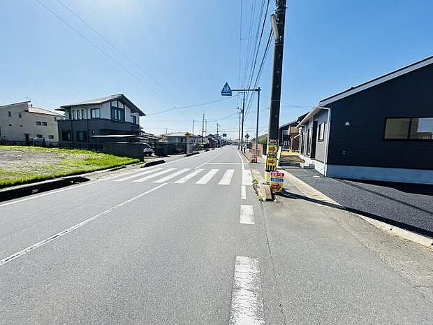 前面道路は広々としており車の出入りもスムーズに行えます。周辺には住宅が整然と並び落ち着いた雰囲気があります。歩道も確保されていて通行にも配慮されています。近隣の街並みがよく分かる現地写真です。