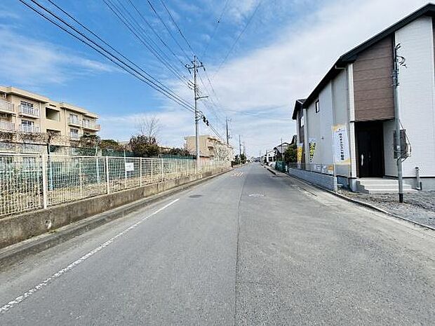 前面道路は見通しが良く車の通行がしやすい環境です。周囲には建物やフェンスが整っており整然とした印象を与えます。電柱や配線もきちんと整備されています。住環境の雰囲気がわかりやすい立地です。