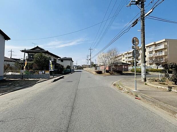 広々とした前面道路が印象的な現地写真です。車の出入りがしやすく周辺は開放感があります。電柱や標識が整然と配置されており落ち着いた街並みが伺えます。道幅が確保されているため移動にも便利な環境です。