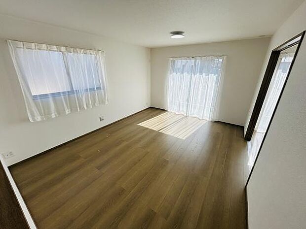 二面に窓があり日差しがたっぷりと入るリビングです。シンプルな内装で家具の配置がしやすい空間になっています。フローリングは落ち着いた色合いでお部屋全体に温かみを感じられます。