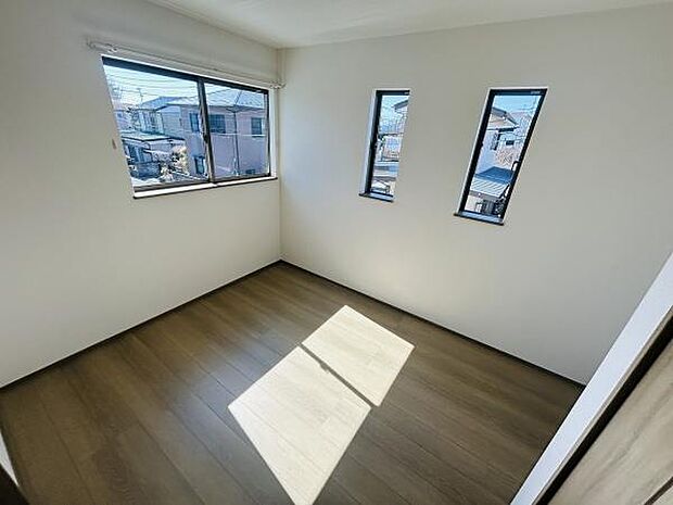 三面に配置された窓から自然光がたっぷり入る洋室です。シンプルな内装が様々なインテリアに調和します。角部屋ならではの開放感を感じられます。木目調の床が落ち着いた雰囲気を演出しています。