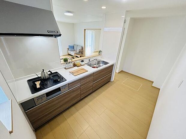 開放感のあるキッチンが特徴です。ナチュラルなカラーの床材が空間を明るく見せます。ダイニングスペースとの繋がりを感じられます。作業スペースもしっかり確保されています。全体的にすっきりとした印象です。