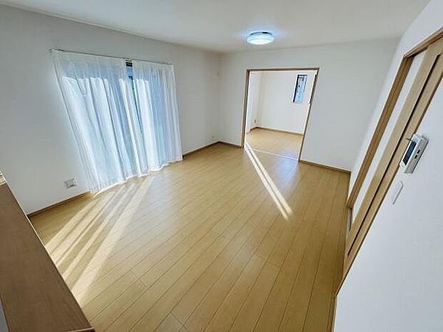 リビングは大きな窓から光が差し込み明るさが魅力的です。壁と床の色合いが調和しており室内が広く感じられます。隣接する部屋とのつながりがあり開放感が得られます。