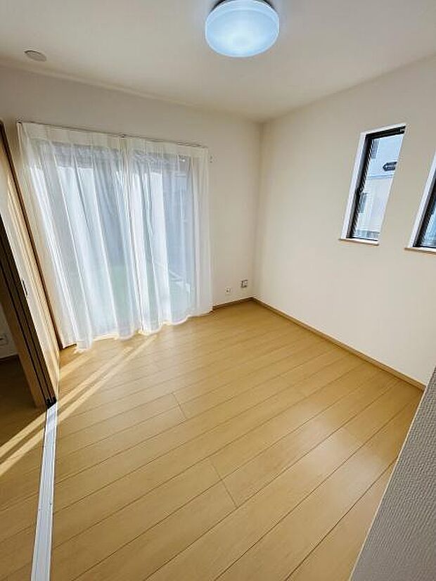明るい光が差し込む洋室です。二面採光で室内が開放的な印象です。床はナチュラルな色味で空間がすっきりとしています。シンプルな内装が好印象です。バルコニーへの出入りもスムーズに行えます。