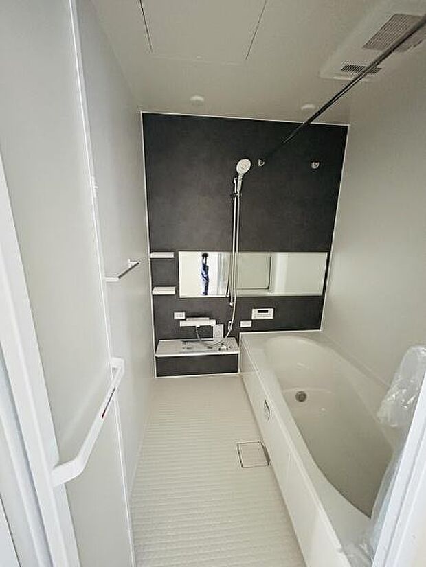 シックなアクセントパネルが空間に落ち着いた雰囲気をもたらします。ワイドな鏡が設置されており視覚的な広がりを感じられます。ゆったりとした浴槽が特徴的でお手入れのしやすさも考慮されたバスルームです。