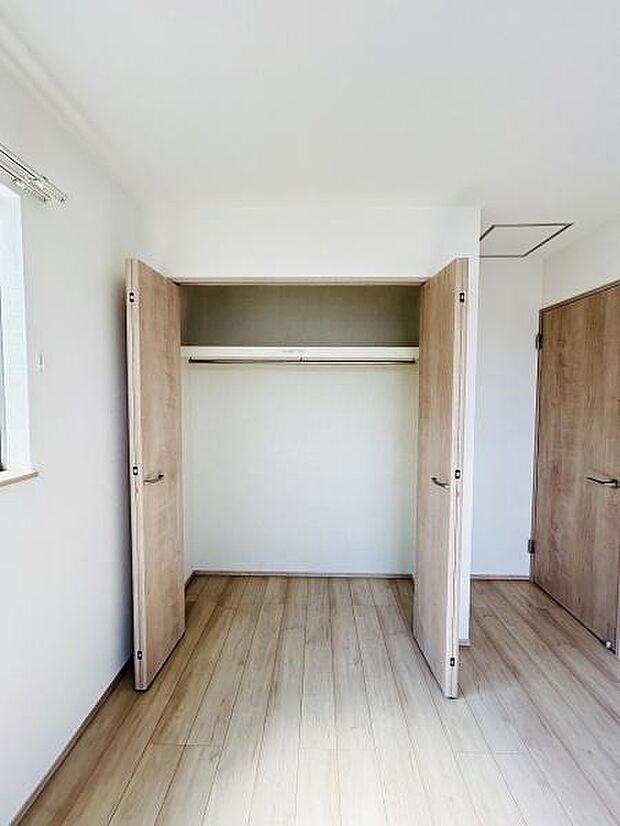 シンプルなデザインの収納スペースが設けられています。両開きの扉が使いやすく室内の明るさを損なわない配置です。内装の色合いは落ち着いており整った印象を与えます。収納の高さも十分に確保されています。