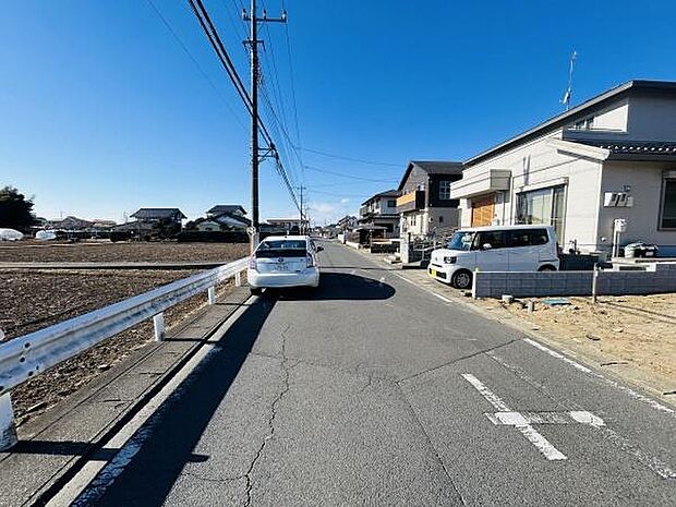 前面道路は見通しが良く車のすれ違いもしやすい幅員です。周囲には住宅が並び落ち着いた街並みが広がっています。現地の雰囲気が分かりやすい写真で周辺環境の様子も伝わります。