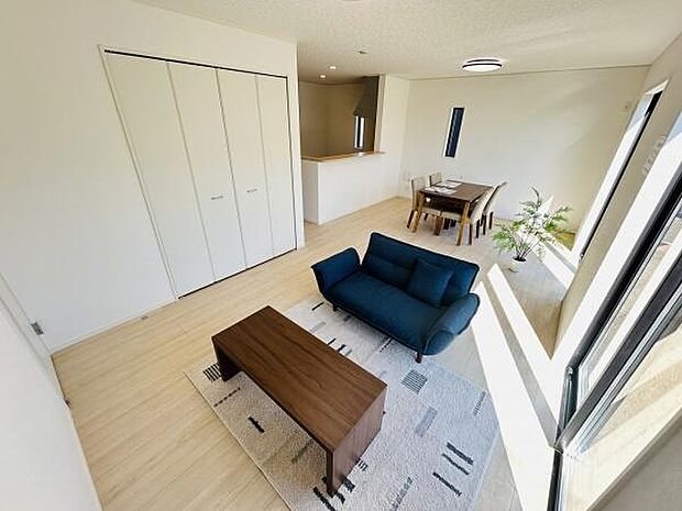 大きな窓からたっぷりと自然光が入るリビングです。明るい床材で清潔感があります。家具が配置しやすいシンプルな形状です。ダイニングスペースも併設されています。収納も備わっています。