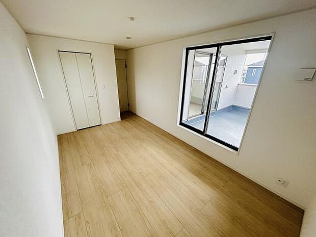 明るい光が差し込む寝室です。バルコニーに面した大きな窓が開放感を演出します。シンプルな内装で使いやすい空間です。収納スペースも備えています。床はナチュラルな雰囲気の仕上げです。