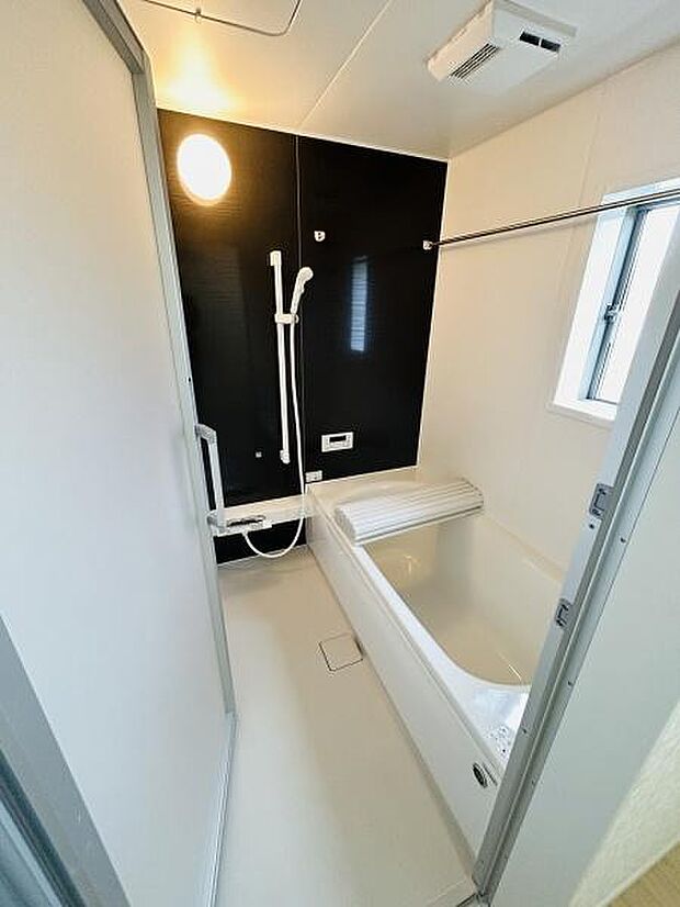 シンプルで清潔感のあるバスルームです。大きめの窓があり換気や明るさも確保されています。浴槽にはカバーがついており使い勝手が良いです。壁面は落ち着いた色合いで空間を引き締めています。