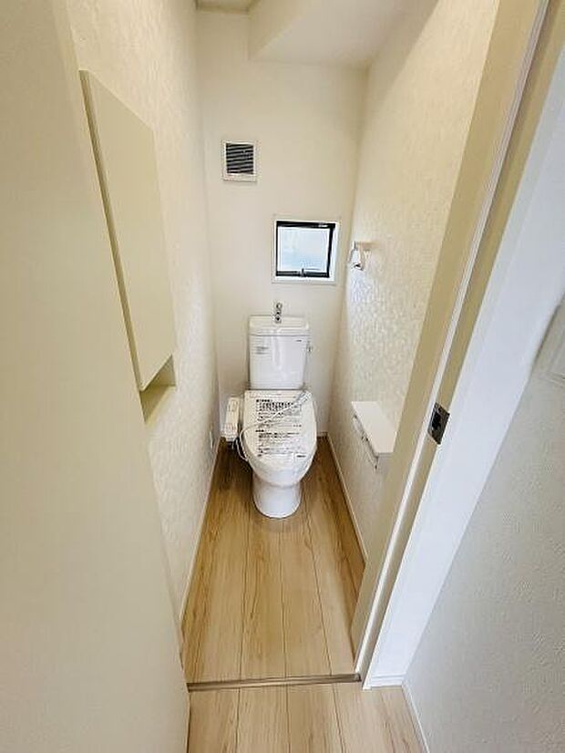 シンプルで清潔感のあるトイレです。小窓があり空気の入れ替えもしやすい設計となっています。床は木目調で落ち着いた雰囲気が感じられます。限られたスペースを有効活用したレイアウトです。