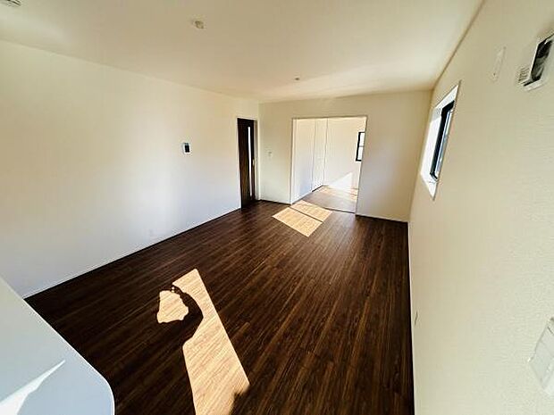 リビングには大きな窓があり日差しがしっかりと差し込む明るい空間です。床は落ち着いた色合いでどんなインテリアにも合わせやすいデザインになっています。壁や天井もシンプルに仕上げられており開放感があります。