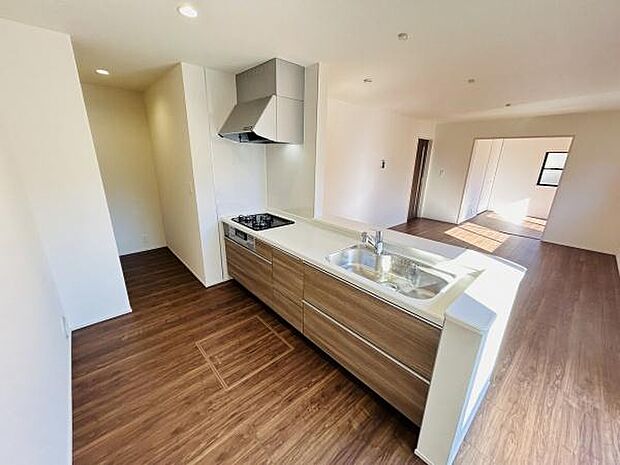 開放感のあるキッチンはリビングと一体化したデザインです。木目調の床と扉が温かみを感じさせます。作業スペースも広く収納も豊富です。日当たりも良好で明るい雰囲気です。