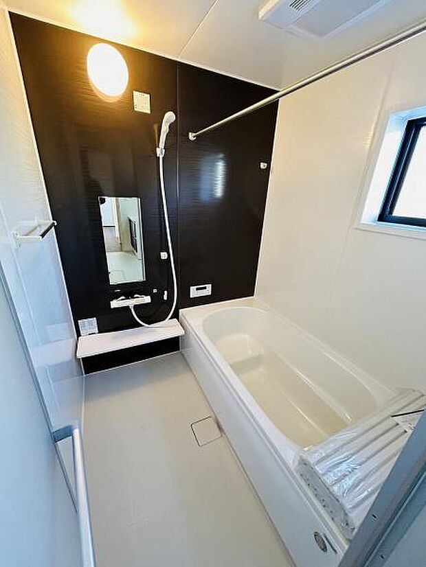 バスルームはシンプルなデザインで清潔感があります。壁のアクセントカラーが空間を引き締めています。明るい照明と窓からの自然光で開放的な印象です。使いやすい浴室仕様となっています。