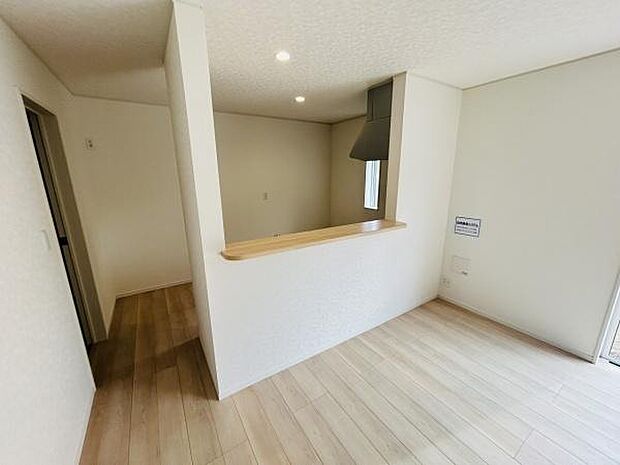 明るい色合いの床材が空間全体をすっきりと見せています。キッチンカウンターがリビングに面しており開放感を感じられます。窓からの自然光が室内を照らし快適な雰囲気が広がります。