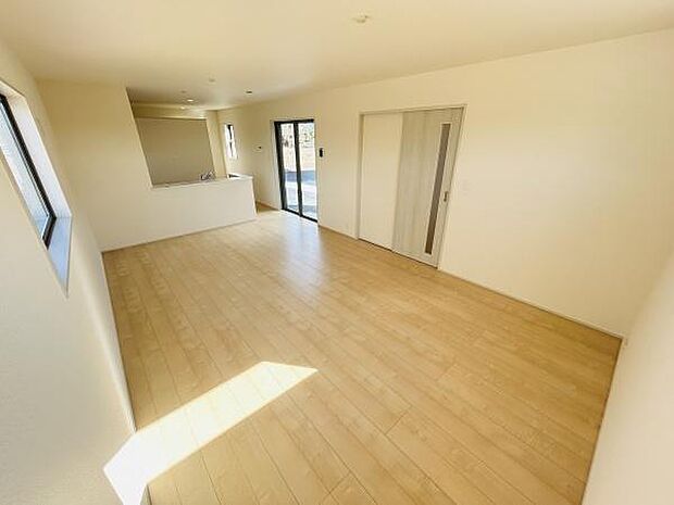 明るい色合いのフローリングが印象的なリビングです。大きな窓から自然光がたっぷり入り開放感があります。キッチンとの一体感も感じられる間取りです。スライドドアの設置で空間を有効に使えます。