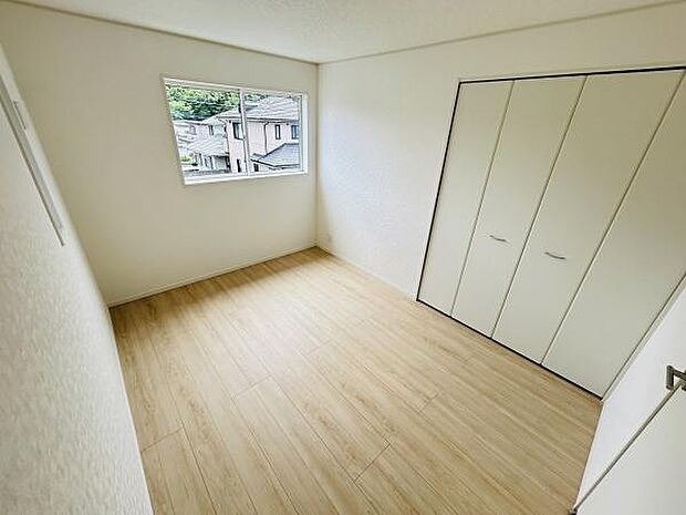 洋室は落ち着いた色合いのフローリングが採用されています。クローゼットも備わっており収納スペースがしっかり確保されています。窓からは外の眺めも楽しめる設計です。全体的に明るく清潔感のある空間です。