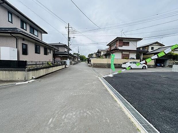 前面道路は幅があり車の出し入れがしやすそうです。周囲には住宅が並び落ち着いた雰囲気が感じられます。現地の状態もきれいに整えられており印象に残る一枚です。住環境をイメージしやすい写真です。