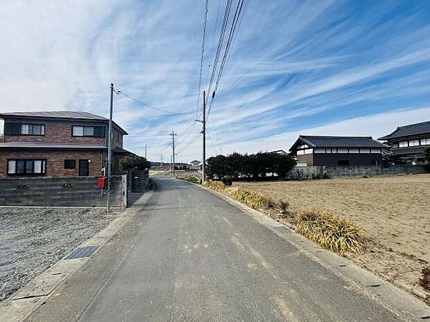 周囲に建物が少なく空が広く感じられる前面道路の現地写真です。道路幅がしっかりと確保されており車の出入りも安心です。周辺は開放感があり落ち着いた住環境が整っています。