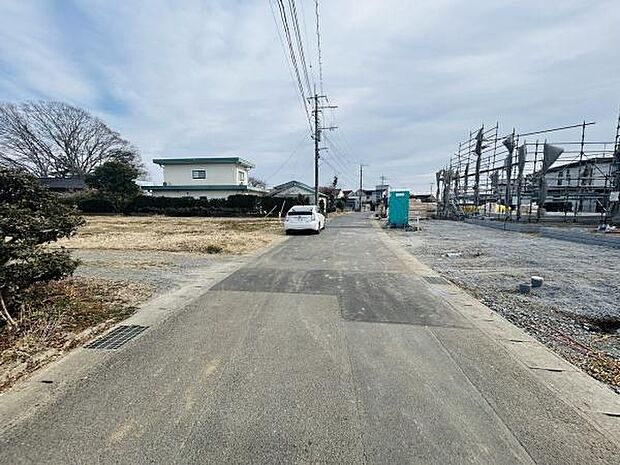 現地前面道路は広く車の出入りもスムーズに行えます。周辺は開放的な雰囲気があり建築中の現場も近くに見えます。電柱や舗装も整っていてアクセスしやすい環境です。