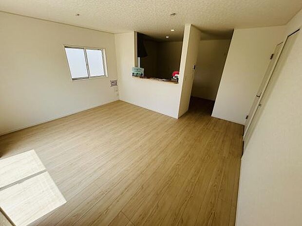 リビングは明るい光が差し込み開放的な雰囲気を感じられます。床は木目調で温かみがあります。壁や天井はシンプルなデザインとなっています。窓からの自然光が空間をより広く感じさせます。