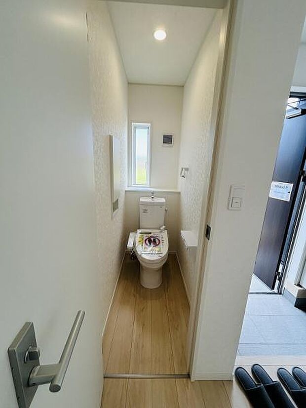 トイレは明るい空間で窓が設置されているため換気もしやすい仕様です。清潔感のあるデザインが印象的です。床材と壁紙が調和しており落ち着いた雰囲気です。コンパクトながらも機能的なトイレです。
