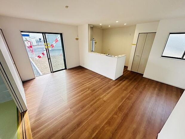 広々とした空間が広がるリビングです。南向きの大きな窓から自然光がたっぷり入ります。キッチンとリビングがつながり開放感があります。床は木目調で落ち着いた雰囲気です。収納スペースも確保されています。