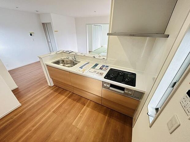 ナチュラルな木目調のキッチンが空間全体を明るく演出します。使いやすいシンクとコンロが機能的に配置されています。お手入れしやすいカウンタートップが魅力です。