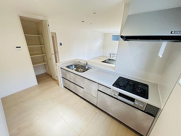 シンプルで広々としたキッチンです。収納スペースが充実しており整理しやすい仕様です。シンクとコンロが使いやすい位置に配置されています。パントリーもあり収納が充実しています。清潔感のある空間です。