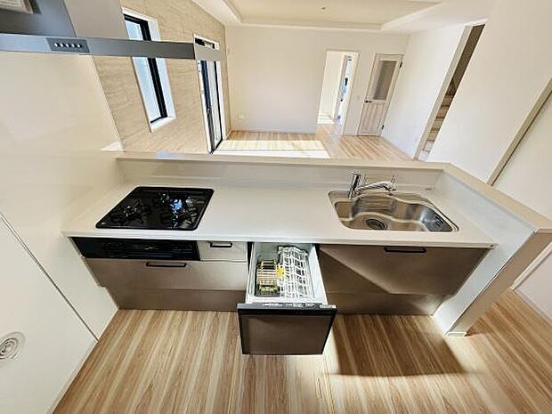 広々としたキッチンには使い勝手の良いシンクとガスコンロが備わっています。ビルトインタイプの食洗機が設置されており日々の家事も快適です。清潔感のあるカウンターと明るい床材が空間を引き立てています。