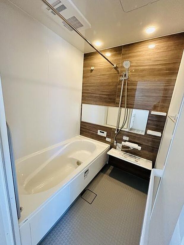 木目調のアクセントパネルが落ち着いた雰囲気を演出しています。ワイドなミラーと充分な収納スペースがございます。清潔感のあるバスタブで日々の疲れを癒やせます。
